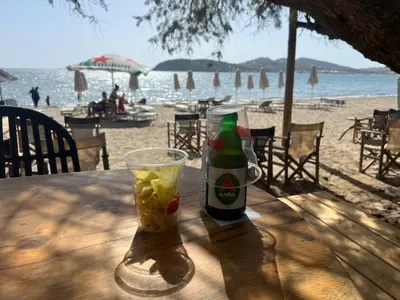 a bottle of beer sitting on a table at the beach at Athens Palaia Fokaia Entire Flat 2 bedrooms with panoramic sea views and a massive veranda , only steps away from the beach and amenities in Palaiá Fókaia