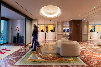 a woman walking through a lobby with a couch and a person at Astor Hotel Athens in Athens