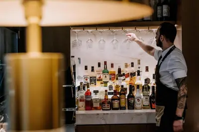 a man standing in front of a refrigerator filled with bottles at Astor Hotel Athens in Athens