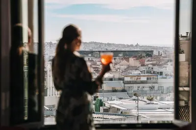 a woman standing in front of a window looking at a city at Astor Hotel Athens in Athens