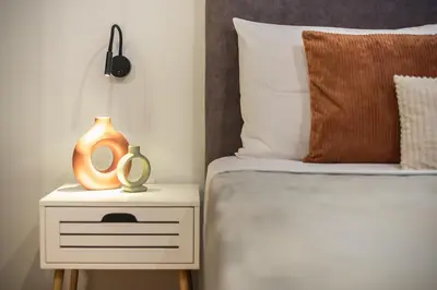 a bed with a side table with a vase on it at Athens Home in Athens