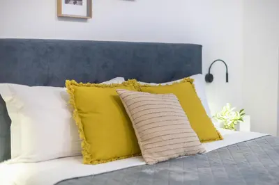 a bed with white pillows and yellow pillows at Home In Athens in Athens
