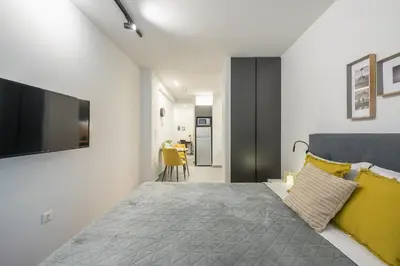 a bedroom with a bed with yellow pillows and a television at Home In Athens in Athens