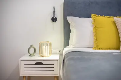 a bed with a yellow pillow and a night stand at Home In Athens in Athens