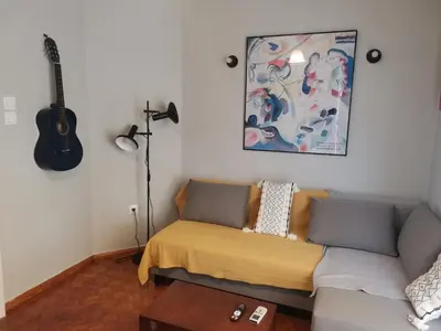 a living room with a couch and a guitar on the wall at Υπέροχο διαμερίσμα στο κέντρο της Αθήνας in Athens