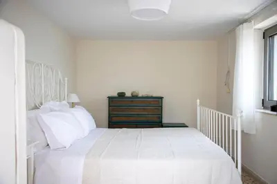 a white bedroom with a white bed and a window at Sea La Vie in Agia Marina Aegina