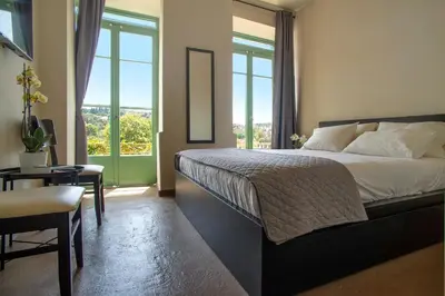 a bedroom with a bed and a table and windows at Ancient Agora Plaka in Athens
