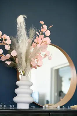 a vase with feathers and flowers in front of a mirror at Sea-View Apt Argyroupoli, Athens in Athens