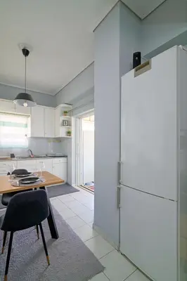 a kitchen with a table and a refrigerator at Sea-View Apt Argyroupoli, Athens in Athens