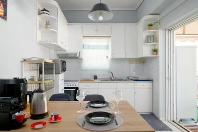a kitchen with a wooden table with two wine glasses at Sea-View Apt Argyroupoli, Athens in Athens