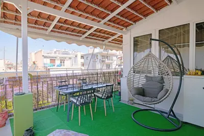 a porch with a hammock and a table and chairs at Sea-View Apt Argyroupoli, Athens in Athens
