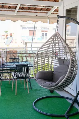 a hanging hammock on a patio with tables and chairs at Sea-View Apt Argyroupoli, Athens in Athens