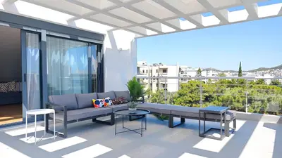 a patio with a couch and a table on a balcony at Costa Voula Private Pool Penthouse by the Beach in Athens