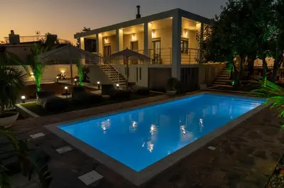 a swimming pool in front of a house at night at Mezcal Private Pool Villa in Kalívia Thorikoú