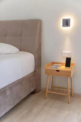 a nightstand with a bed and a table with a laptop on it at Parthenon view apt in Athens