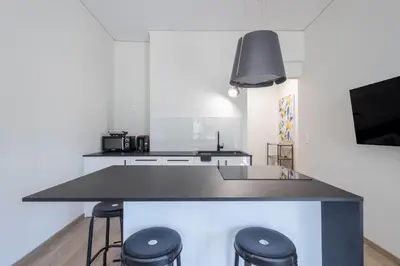 a kitchen with a black counter top and stools at Elegance Suite Stunningly Renovated in Athens