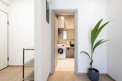 a hallway leading to a kitchen with a washing machine at Elegance Suite Stunningly Renovated in Athens