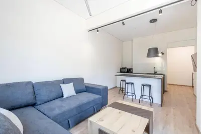 a living room with a blue couch and a kitchen at Elegance Suite Stunningly Renovated in Athens
