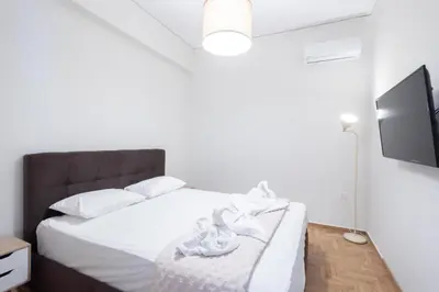 a bedroom with a white bed and a flat screen tv at Modern 2-Bedroom Gem close to Metro in Athens