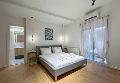 a white bedroom with a bed and a large window at LIV - Modern Comfort Oasis in Pagrati in Athens