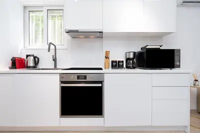 a kitchen with white cabinets and a black dishwasher at Stylish Apartment in Athens Riviera with Outdoor Patio in Athens