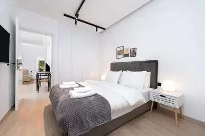 a white bedroom with a large bed and a desk at Stylish Apartment in Athens Riviera with Outdoor Patio in Athens