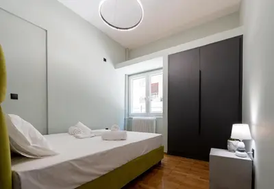 a bedroom with a bed with white sheets and a black door at LIV - Comfortable Designer Apt in Lycabettus in Athens