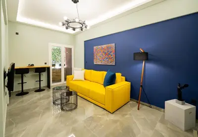 a yellow couch in a living room with a blue wall at LIV - Comfortable Designer Apt in Lycabettus in Athens