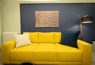 a yellow couch in a living room with a painting at LIV - Comfortable Designer Apt in Lycabettus in Athens