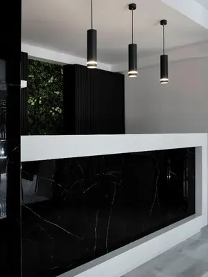a black and white reception counter with three pendant lights at AVA Hotel & Residences Athens Riviera in Athens
