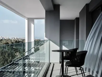 a glass balcony with a table and chairs on it at AVA Hotel & Residences Athens Riviera in Athens