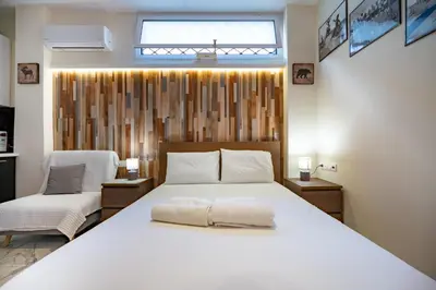a bedroom with a large white bed and a chair at Cozy Studio at Vyronas for 2 pers by MPS in Athens