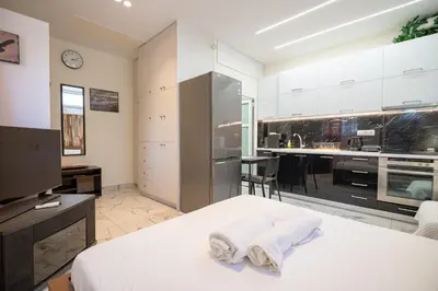 a bedroom with a white bed and a kitchen at Cozy Studio at Vyronas for 2 pers by MPS in Athens