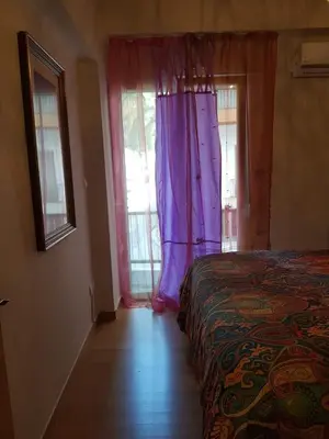 a bedroom with a bed and windows with purple curtains at Urban by the Sea in Piraeus