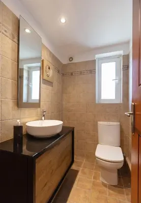 a bathroom with a sink and a toilet and a mirror at Holiday Maisonette in Varkiza by GHH in Vari