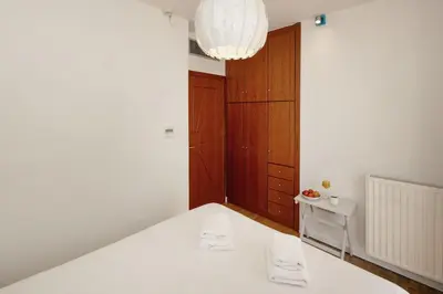 a white room with a bed and a chandelier at Holiday Maisonette in Varkiza by GHH in Vari