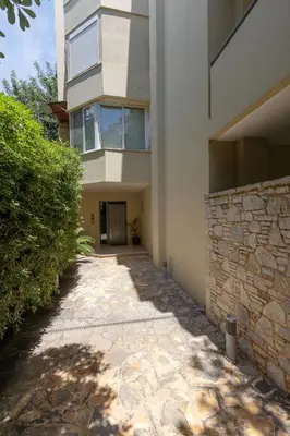 a building with a stone wall next to a walkway at Holiday Maisonette in Varkiza by GHH in Vari