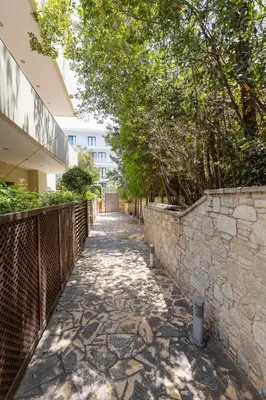 a walkway between a building and a stone wall at Holiday Maisonette in Varkiza by GHH in Vari