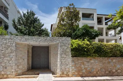 a stone retaining wall with a garage in front of a building at Holiday Maisonette in Varkiza by GHH in Vari