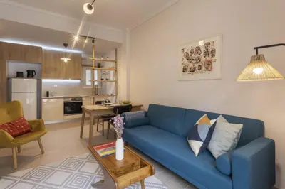a living room with a blue couch and a kitchen at SpyrouTrikoupi36-Cozy 1BDR Apartment near Archaeol in Athens