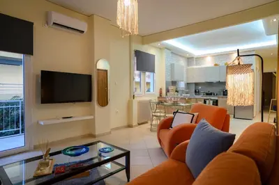 a living room with orange couches and a tv at Salty 2bed Bliss and Comfort in Athens