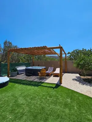 a pergola with a table and chairs on a lawn at St'Georges garden house in Palaiá Fókaia