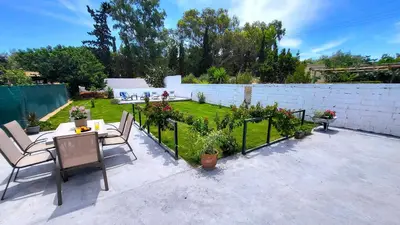 a patio with a table and chairs and a garden at Mini-villa Central Park near the beach in Lagonissi