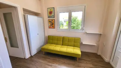 a yellow couch in a room with a window at Mini-villa Central Park near the beach in Lagonissi