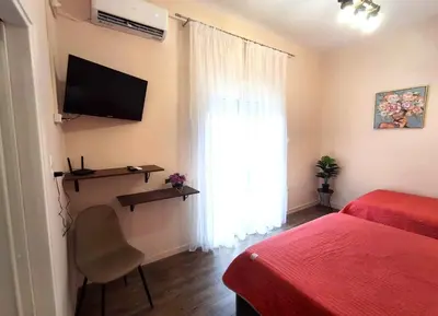 a bedroom with a bed and a television and a window at Mini-villa Central Park near the beach in Lagonissi