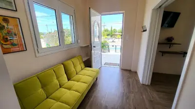a yellow couch in a living room with a window at Mini-villa Central Park near the beach in Lagonissi