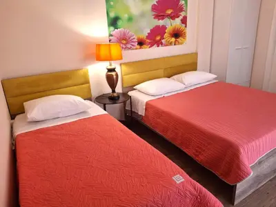 two beds in a small room with a lamp at Mini-villa Central Park near the beach in Lagonissi