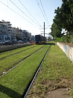 a train traveling down the tracks on a city street at Alimos Kalamaki 100 meters from the Beach in Athens
