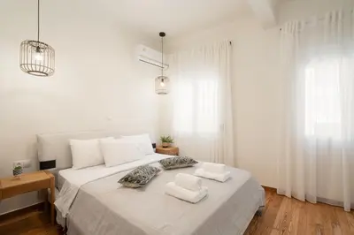 a white bedroom with a large bed with two pillows at LIV - Charming 3BD in Athens Vibrant Downtown in Athens