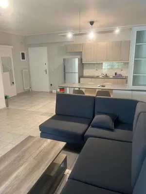 a living room with a blue couch and a kitchen at Neos Kosmos Cozy Retreat - Central Comfort in Athens